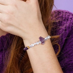 Detail van amethist armband met zoetwaterparels en gouden kralen om de pols van een model