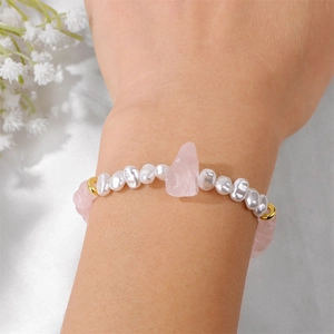 Detailopname van onregelmatige parels en rozenkwarts armband met gouden accenten