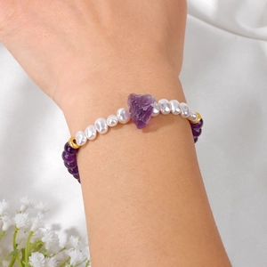 Detail van 6mm paarse amethist armband met witte parels en ruwe steen om de pols