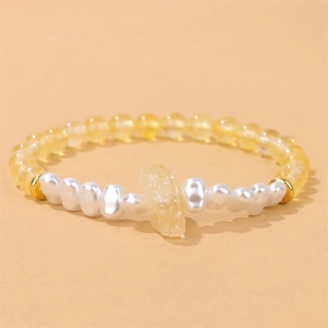Detail van handgemaakte elastische armband met gele kristallen kralen en barokke parel