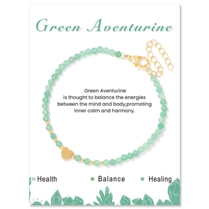 Macro detail of 3mm green aventurine faceted beads with gold heart charm on jewelry card