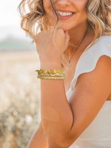Detailed view of triple-layered natural yellow crystal bead bracelets on a woman's wrist