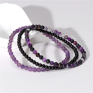 Detail of 4mm natural amethyst and black agate elastic bead bracelets on white ceramic plate