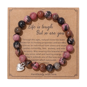 Detalle de pulsera de cuentas de piedra cebra rosa con colgante de corazón en tarjeta