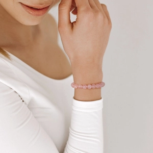 Close-up of 8mm pink zebra crystal beads bracelet worn on a woman's wrist with white outfit