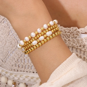 Gros plan d'un ensemble de quatre bracelets en perles d'eau douce et billes dorées