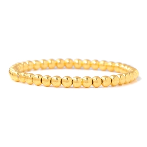 Vue détaillée de perles rondes en métal doré poli sur un bracelet extensible minimaliste