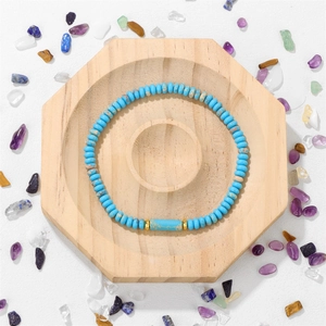 Detalle de pulsera de jaspe imperial azul con espaciadores dorados en bandeja madera