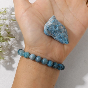 Detalle de pulsera de apatita azul de 8 mm en la muñeca con un cristal natural en bruto