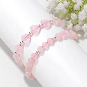 Detail von rosa Kristallperlenarmbändern mit Herzform auf weißem Zylinderständer