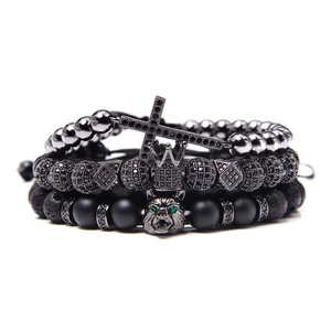 Makroansicht schwarzer Natursteinarmbänder mit Krone, Kreuz und Wolfskopf-Anhänger