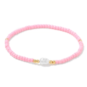 Détail de perles roses et une perle baroque sur un bracelet extensible doré