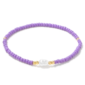 Gros plan de perles lavande et perle blanche irrégulière sur bracelet doré chic