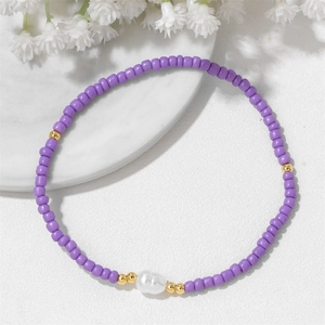 Détail d'un bracelet en perles violettes avec accents dorés et une perle blanche centrale