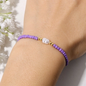 Gros plan sur bracelet bohème en perles violettes avec perle naturelle et détails or 18k