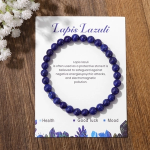 Close-up of lapis lazuli beaded bracelet on white card over natural wood background