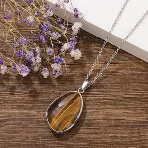 Detail view of water-drop tiger eye stone pendant on a silver stainless steel chain