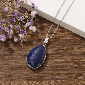 Lapis lazuli teardrop pendant necklace on silver chain over rustic wood background