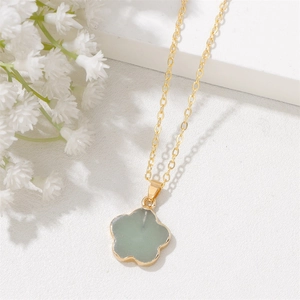 Macro di una collana a catena dorata con un ciondolo a forma di petalo verde chiaro