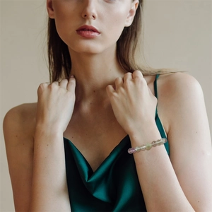 Detail eines bunten Naturstein-Armbands, getragen von einem Model im Satin-Kleid