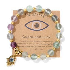 Détail d'un bracelet en perles de pierre avec breloque main de Fatma dorée et œil protecteur