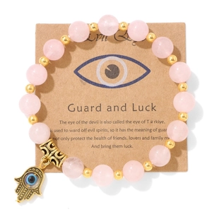 Détail d'un bracelet en perles roses avec breloque main de Fatma et œil maléfique