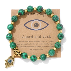 Détail des perles en malachite verte et main de Hamsa dorée avec l'œil protecteur