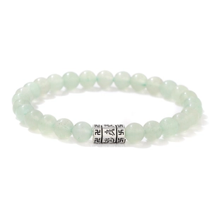 Macro detail of 6mm light green jade beads with engraved silver mantra charm on bracelet