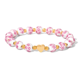 Detailed macro of white porcelain bead bracelet with pink floral motifs and gold heart charm