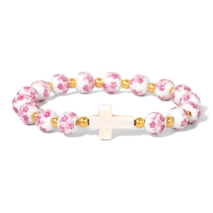 Macro detail of porcelain beads with pink floral patterns and golden spacers on the bracelet