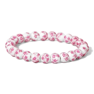 Close-up of white ceramic beads with pink floral patterns on an elastic bracelet