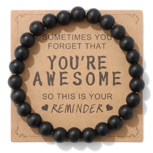 Detail van matte zwarte kralenarmband op kraft kaart met inspirerende tekst als cadeau