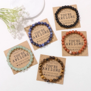 Detail van vijf natuurstenen kralenarmbanden op kraftkaarten met inspirerende tekst