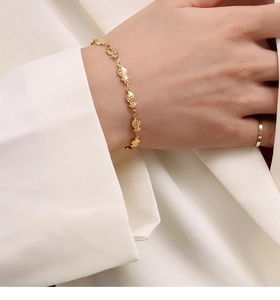 Detail van een vergulde vis-schakelarmband en minimalistische ring om de hand van een model