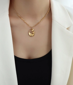 Primer plano de collar con colgante de tulipán de oro 18k sobre un blazer blanco