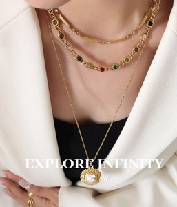 Close-up of layered gold necklace with gemstone links and round medallion pendant