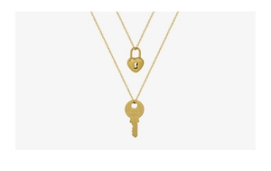 Detailed view of polished 18k gold heart lock and key pendants on fine chain necklaces