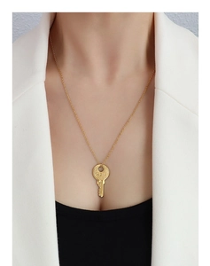 Close-up of gold key pendant with engraved number 121 on a fine link chain necklace