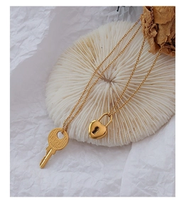 Macro detail of 18k gold heart lock and engraved key pendant on delicate O-chain