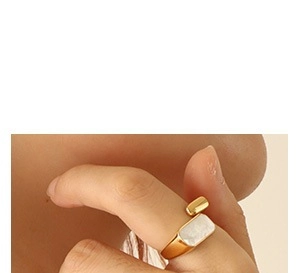 Detail of adjustable gold-plated geometric ring with white rectangular inlay on finger