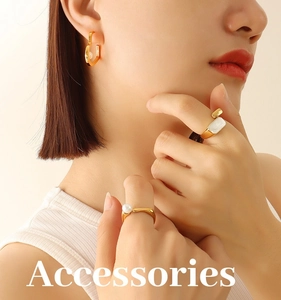 Detailed view of U-shaped gold earrings and minimalist pearl ring worn by a model