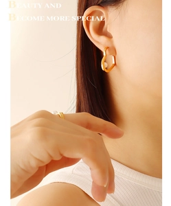 Close-up of heart-shaped gold pearl earrings and ring set worn by a model
