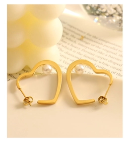 Detail of heart-shaped gold pearl earrings with elegant white pearls on a book background