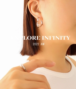 Close-up of minimalist silver heart pearl earrings and matching ring on model
