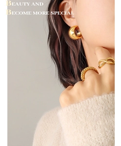 Détail de boucles d'oreilles C dorées polies et bague infini sur un mannequin