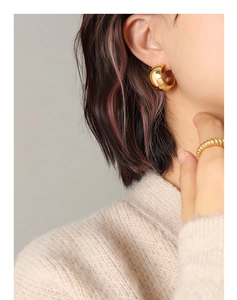 Gros plan de boucles d'oreilles créoles dorées épaisses avec finition miroir polie