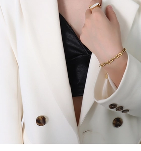 Gros plan d'un bracelet en chaîne dorée et bague rectangulaire sur un mannequin