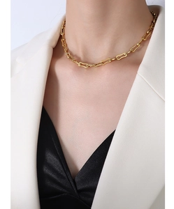 Gros plan d'un collier à maillons géométriques plaqué or 18k porté sur la clavicule
