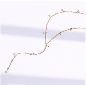 Macro di una sottile collana dorata con eleganti accenti di perle bianche tonde