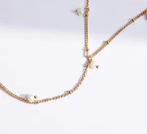 Dettaglio di un'elegante catena dorata con perle naturali d'acqua dolce e maglie rifinite